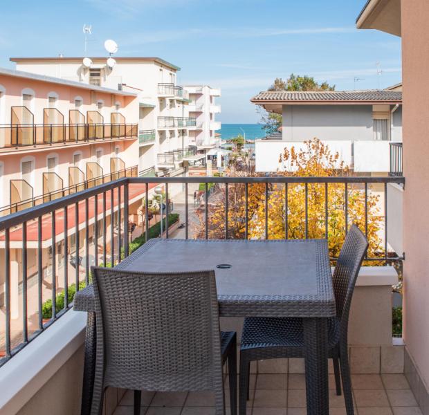 Balcone con vista mare, tavolo e sedie in vimini.