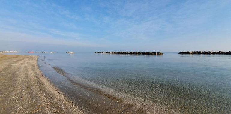 Spiaggia tranquilla con mare calmo e cielo sereno.