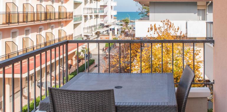 Balcone con vista mare, tavolo e sedie in vimini.