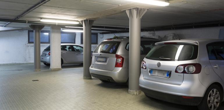 Parcheggio sotterraneo con auto parcheggiate e colonne di supporto.