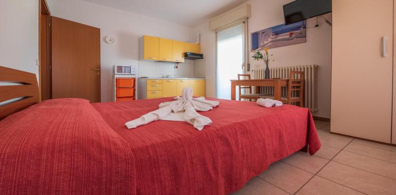 Camera accogliente con letto matrimoniale, cucina e tavolo da pranzo.